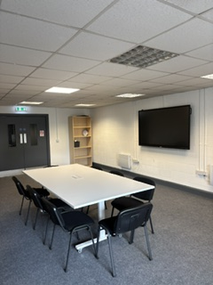Boardroom space with table, seating and display screen
